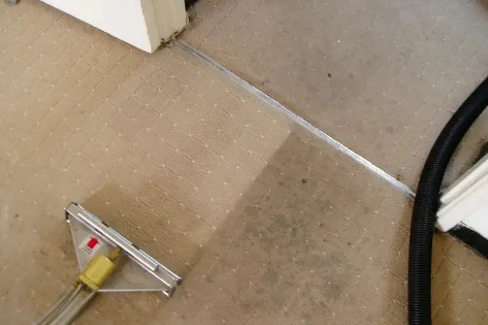 Professional carpet cleaning in Brooklyn, NY showing a clear before-and-after result with deep dirt removal using a steam extraction wand.